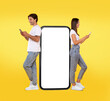 © Prostock-studio - Great App. Excited Couple Leaning On Big Smartphone With Blank White Screen Using Cell Phones, Cheerful Guy And Lady Chatting On Social Media, Standing On Yellow Orange Background, Mock Up, Full Body
