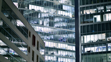 Wall Mural - Office building in the evening with lightened workspaces. Modern, glazed skyscraper in financial district. Late hours in the office.