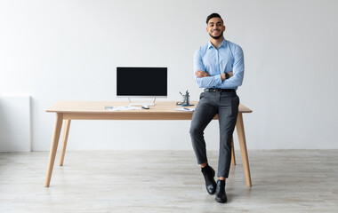 Poster - Mock Up Template. Happy Smiling Arab Man Sitting On Desk Posing With Folded Arms Showing Pc Computer With Blank Black Screen At Home Office, Free Copy Space. People, Technology, Remote Work Concept