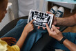 © DragonImages - Dentist showing patient close-up dental x-ray on digital tablet while explaining dental condition and treatment plan in modern clinic