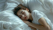 © mahamad - Beautiful young brunette woman sleeping peacefully in a white bed.