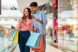 © Prostock-studio - Happy Couple Shopping Using Smartphone And Credit Card Standing In Mall, Holding Colorful Shopper Bags. Buyers Using App Purchasing Clothes Online. Ecommerce Application Concept. Selective Focus