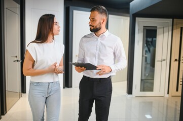 Wall Mural - A salesman advises a female customer on the choice of interior doors in a hardware store