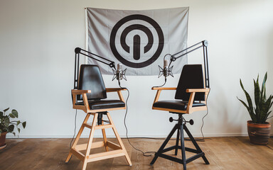 Modern podcast studio setup featuring two microphones and stylish chairs in a bright, minimalist room