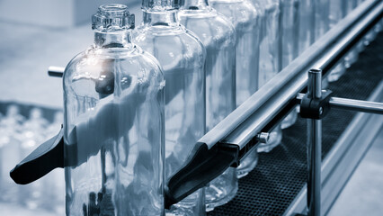 Poster - Glass bottles line on a conveyor belt. Bottles are transparent and clean.