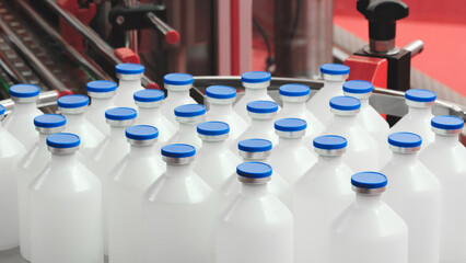 Poster - White plastic bottles with blue caps for medicines and vaccines in a pharmaceutical factory