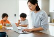 © Running opossum - Asian mother using laptop computer while her sons eating breakfast in kitchen