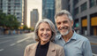 © Елена Пантюхина - Portrait of a couple - Caucasian man and woman, elderly, gray-haired, smiling happy against the background of a city street, modern high-rise buildings.