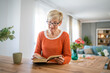 © Miljan Živković - Senior woman mature caucasian female read book at home wear eyeglasses