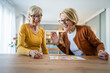 © Miljan Živković - two senior women friends or sisters play leisure board game at home