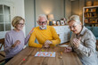 © Miljan Živković - Group of people senior man and women play leisure board game at home