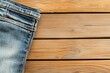 © Nitchalee N. - Jeans style and rugged concept, A close-up of a denim jeans hem resting on a wooden surface, showcasing the texture of both materials.