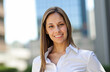 © Minerva Studio - Smiling businesswoman standing in front of office buildings