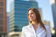 © Minerva Studio - Businesswoman smiling and looking up in a modern city