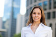 © Minerva Studio - Smiling businesswoman standing in front of office buildings