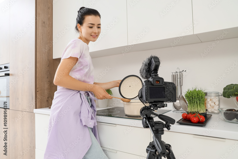 Young woman with soup recording cooking video class in kitchen