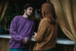 © qunica.com - A young man and woman engage in a casual conversation indoors, creating a relaxed and intimate atmosphere. The setting is cozy with warm tones and soft lighting.