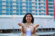 © M Alfan Setyawan - carefree asian young woman holding sparkler celebrate new year eve with laugh and dance in rooftop apartment outdoor with city building background