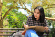 © M Alfan Setyawan - smiling asian beautiful young woman enjoy writing to do list and idea in notebook in outdoors city park