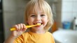 © thesweetsheep - Smiling child brushing teeth with a yellow toothbrush in a bright bathroom setting.