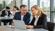 © engincan - Team of diverse partners sitting at table mature Latin business man and European business woman discussing project on laptop in office. Two colleagues of professional business people working together.