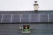 © Halfpoint - Man looking from skylight, roof window with solar panels above him. Sustainable lifestyle and green household.