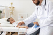 © sofiko14 - Male doctor gives blood transfusion to young Caucasian girl in hospital. Girl lies on bed with comfortable pillows, receiving medical attention. Doctor in lab coat and stethoscope ensures well-being.