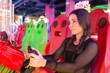 © ADDICTIVE STOCK - Gamer girl enjoying racing game at vibrant arcade center