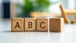 © VirtualVista - Three wooden cubes showing the letters A, B, and C on a white table with a blurred background and empty space for text placement in the lower right corner