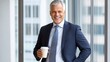 © pkproject - Confident Middle-aged Businessman Smiling and Holding Coffee by Office Window with City View