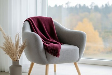 Wall Mural - modern interior design, burgundy throw blanket casually adorns an armchair in a scandinavian-style living room flooded with natural light