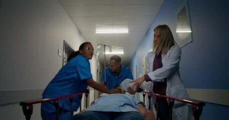 Wall Mural - Medical workers carry a patient on a gurney along the hospital corridor. A woman holds an oxygen mask near his face. They're running