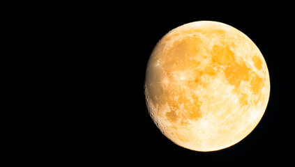 Wall Mural - a large yellow moon is in the sky. the moon is surrounded by a dark background. the moon is the main