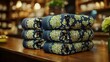 © Borasca - Stack of floral blue patterned fabrics on wooden table in cozy interior setting