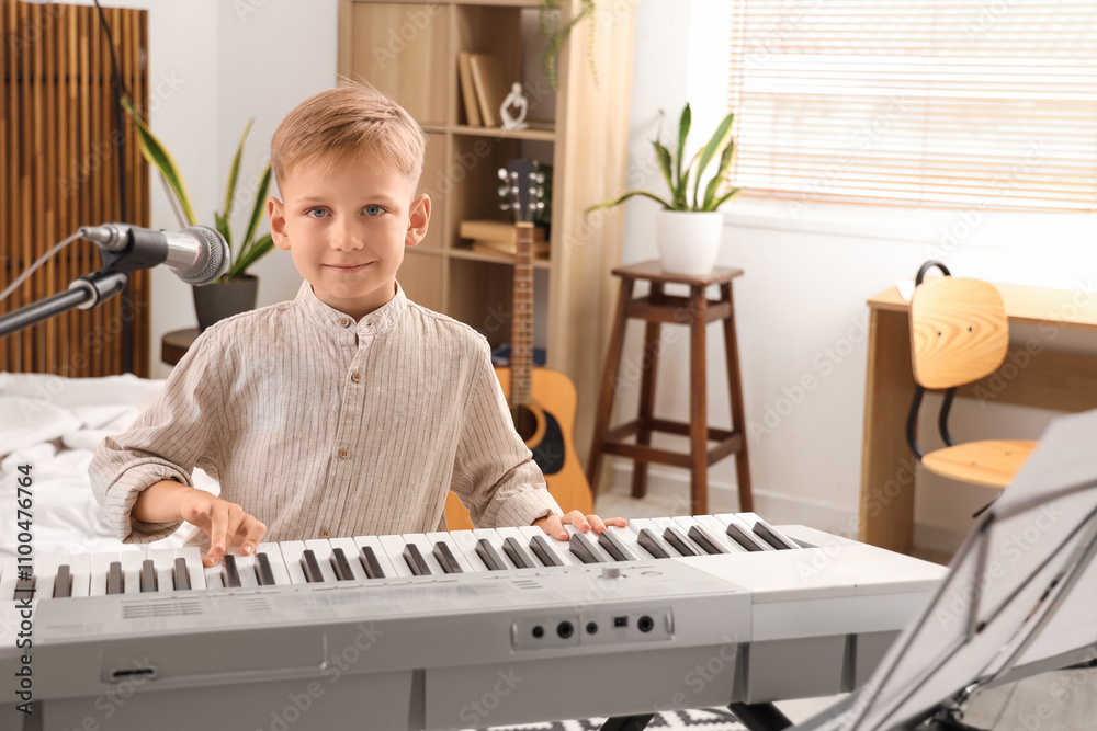 Cute little boy with modern synthesizer and microphone at home