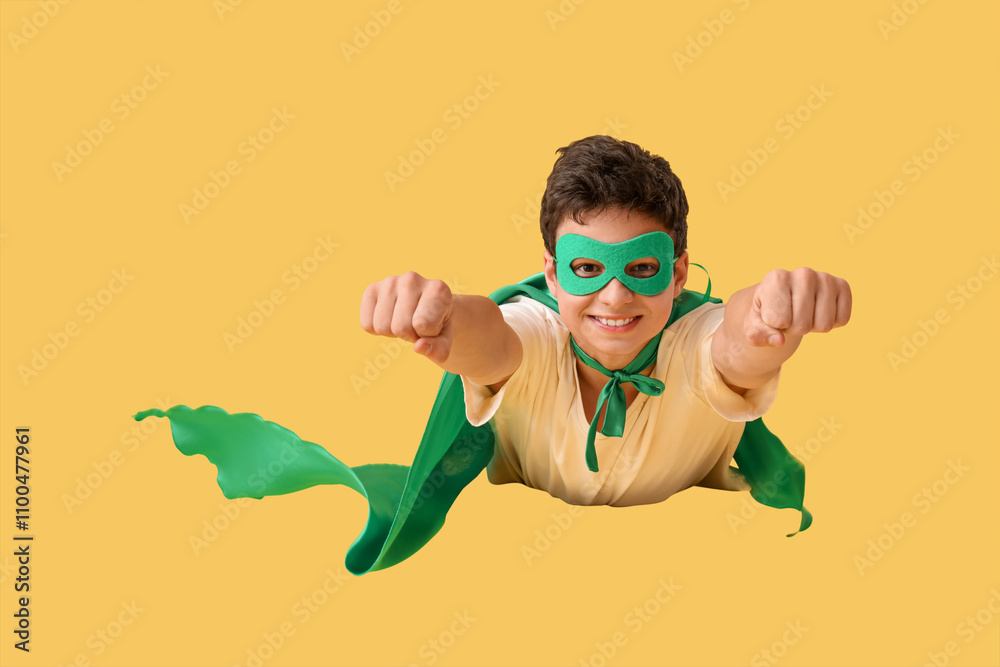 Teenage boy dressed as superhero flying on yellow background