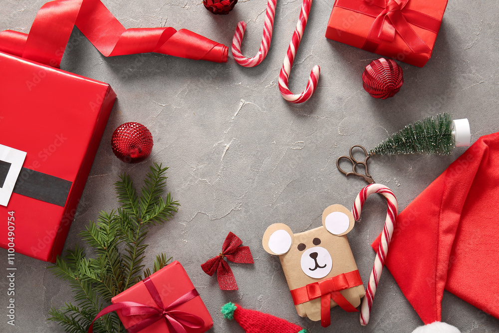 Frame made of gift boxes, candy canes and fir branches on grey background