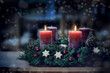 © Maren Winter - Advent wreath with the second lit candle and Christmas decoration outdoors in a patio at night in bluish light, snowy bokeh, copy space, colorized photo, selected focus