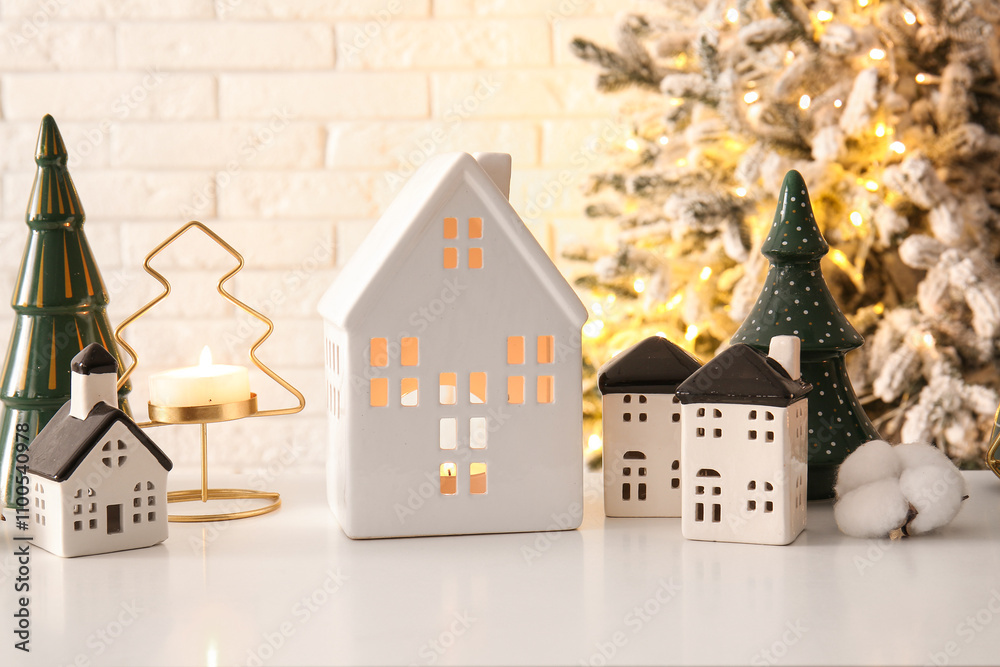 House shaped candle holders with Christmas trees on table in room, closeup