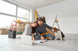© Pixel-Shot - Young couple with plan and Beagle dog sitting during repair in their new house