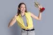 © New Africa - Happy winner with gold trophy cup on gray background