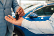 © Zamrznuti tonovi - Close-up of key exchange signifying a new car purchase in showroom.