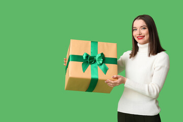 Wall Mural - Young woman holding Christmas gift box on green background