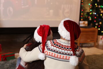 Canvas Print - Young couple watching Christmas movie on projector screen at home, back view