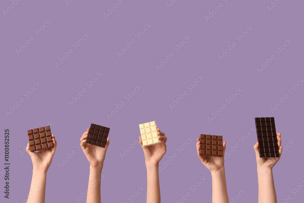 Female hands with different sweet chocolate on lilac background