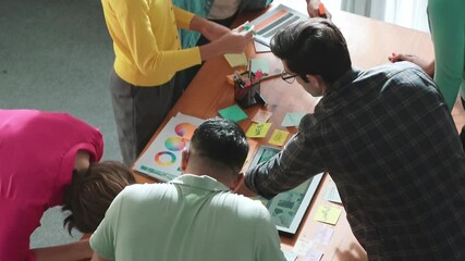 Top view of manager writing idea on sticky notes and explain idea about web design. Professional marketing team or programmer brainstorming idea while looking at tablet with color palette. Symposium.