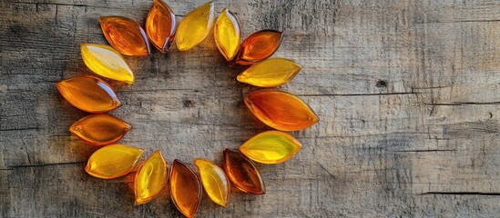 Poster - Colorful glass leaves in a circular arrangement on a rustic wooden background with ample copy space for creative use
