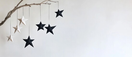 Poster - Stylish black and white paper stars hanging from a wooden branch against a white wall for contemporary festive winter holiday decoration