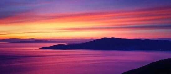 Poster - Colorful sunset over tranquil bay with silhouetted mountains and vibrant sky reflecting on calm water creating a serene atmosphere.