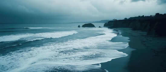 Poster - Serene ocean waves gently rolling onto a rocky beach under an overcast sky during a calm day